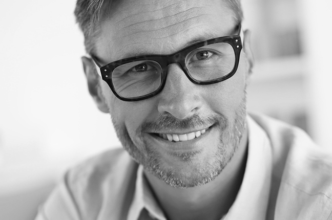 Un uomo indossa occhiali da vista con lenti Zeiss; queste si riconoscono dal certificato di autenticità e da una piccola “Z” incisa