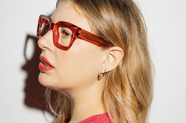 Una ragazza indossa il modello “PATACA” degli occhiali da vista Saraghina, nella versione “ROSSO RUBINO CRISTALLO LUCIDO”